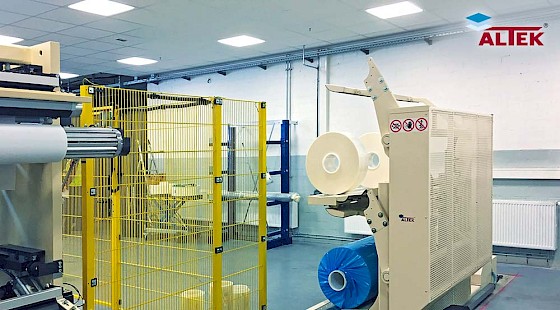 Produktionshalle mit Folienabwicklungsmaschine und gelber Schutzvorrichtung